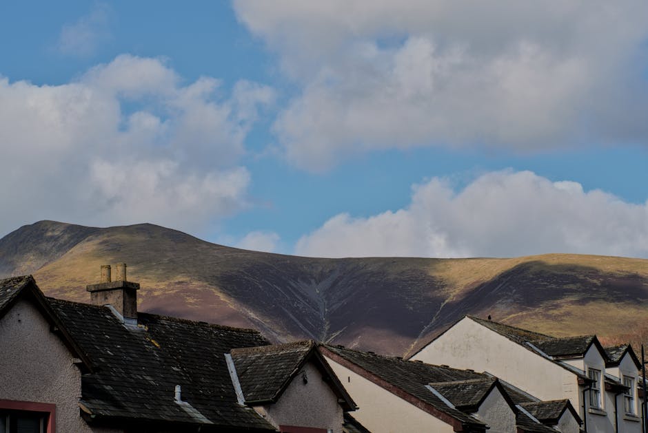 A scenic view of rooftops in Keswick, England with hills and sky in the background.
