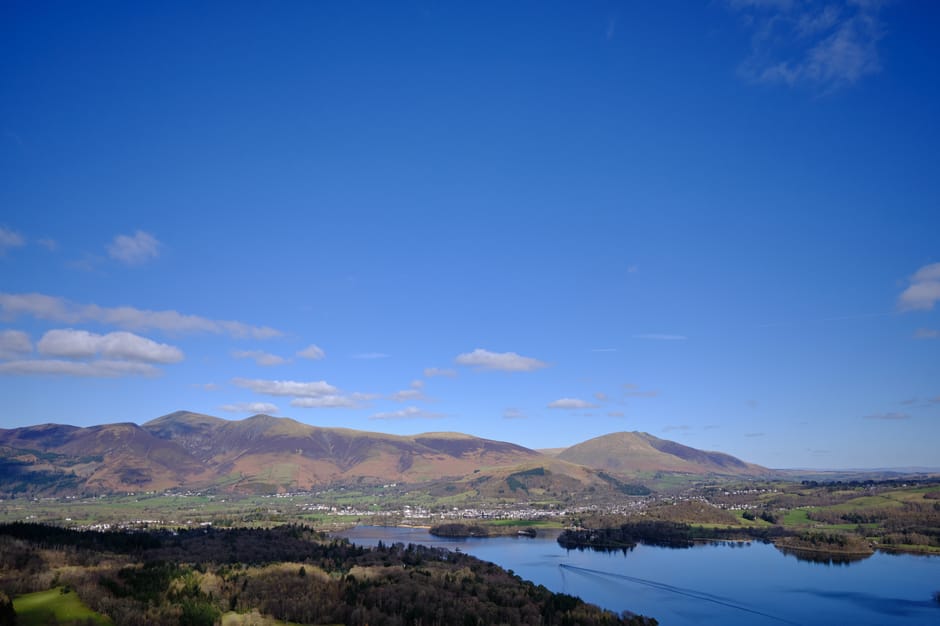 Serene view of Keswick with mountains and lake under a clear blue sky.