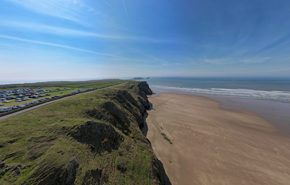 Stunning aerial view of Rhossili Bay's sandy beach and grassy cliffs in Wales.